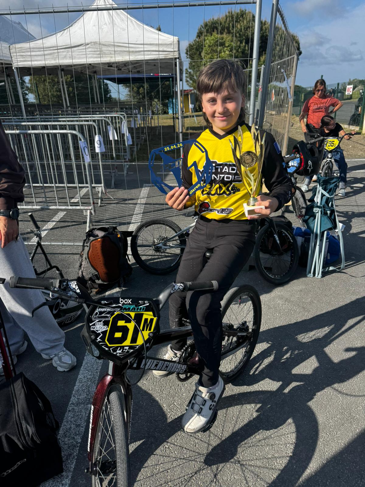 Kéoni MAHI pose avec son vélo BMX et son trophée